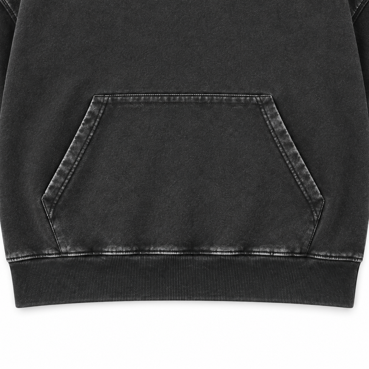 Close-up of the washed black hoodie kangaroo pocket, stitching and ribbed hem.